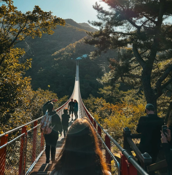 a group of people walking across a suspension bridge